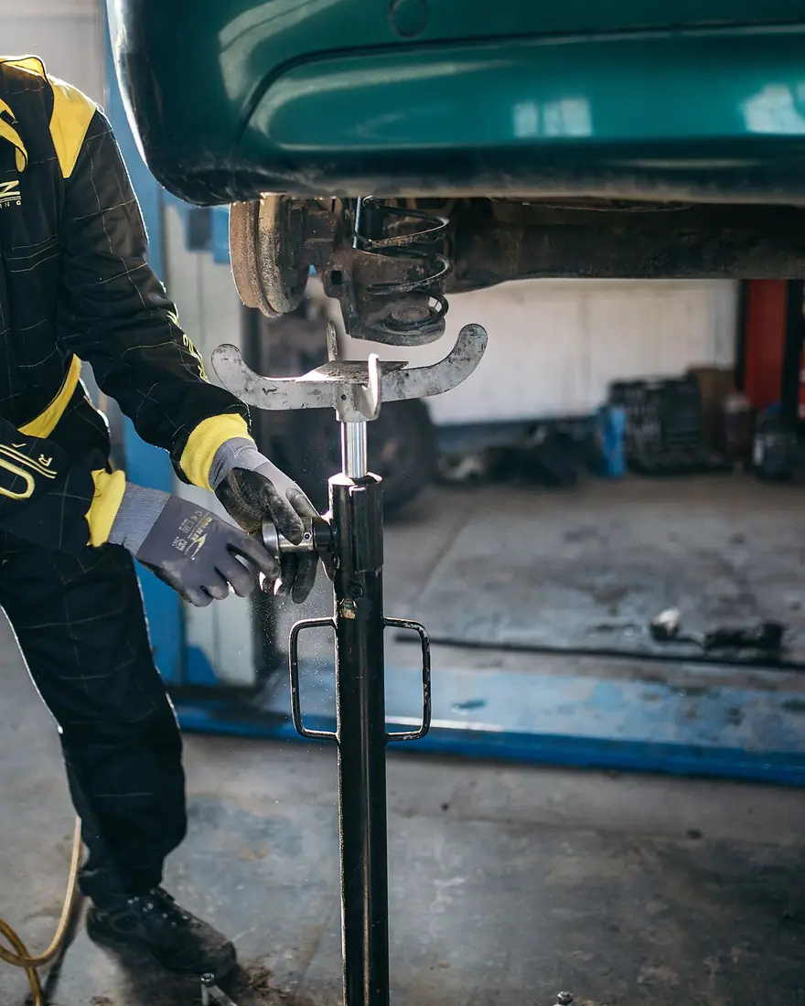 Mechanic working on a car's suspension on a lift